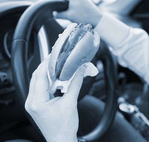 Man eating an hamburger while driving car