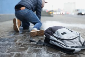 Backpack lying on slippery paving slabs near falling man closeup