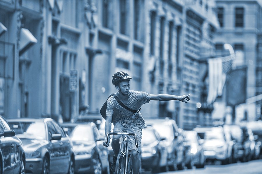 Bicyclist uses hand signals on a busy street.