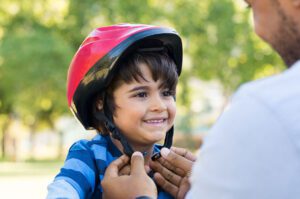 Father fastens bicycle helmet on his son