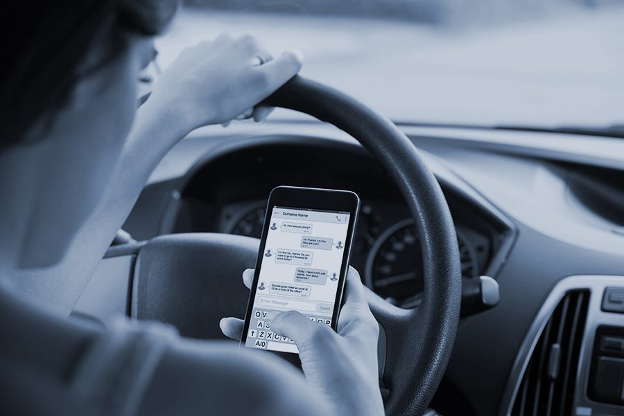 Woman distracted by a text message at the wheel of a car