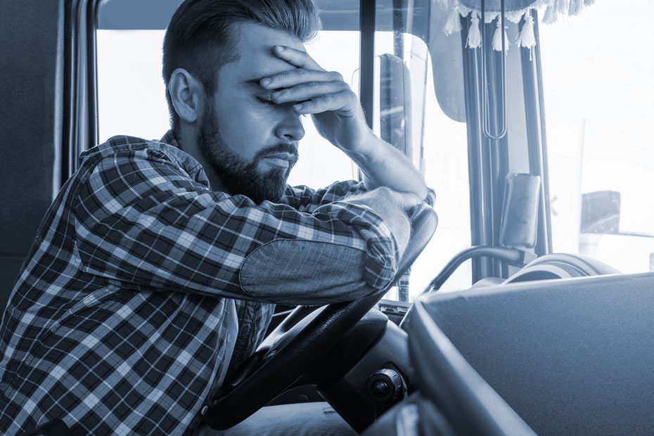 Fatigued man grips his head at the wheel of his Semi- Truck