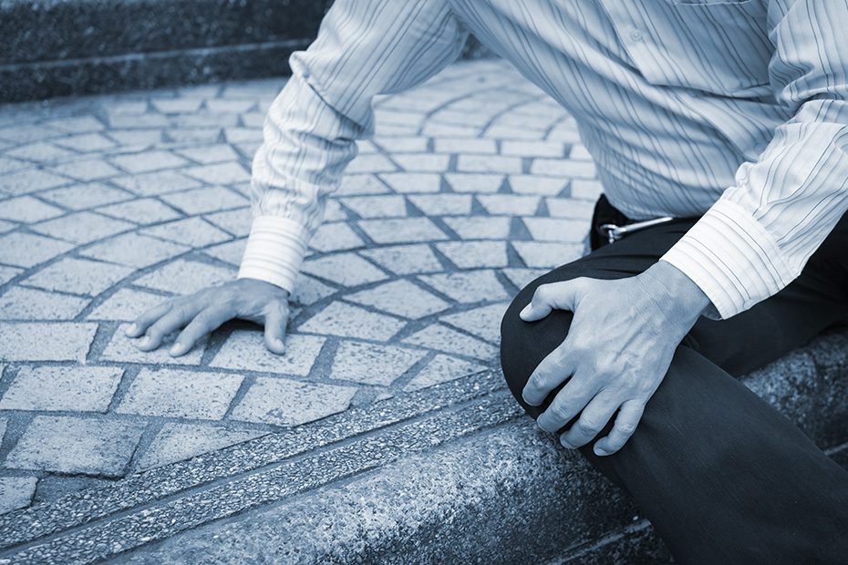 Elderly man grips his knee after falling down