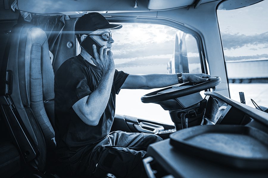 Truck-driver talks on cell phone at the wheel of his big rig