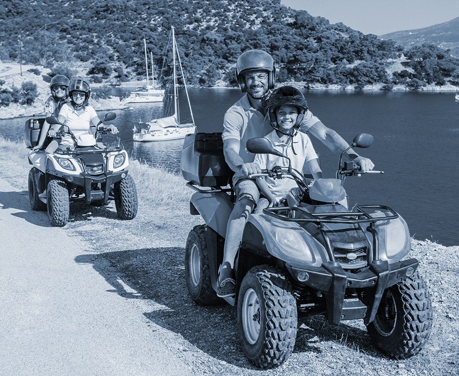 Happy family safely rides ATVs near water