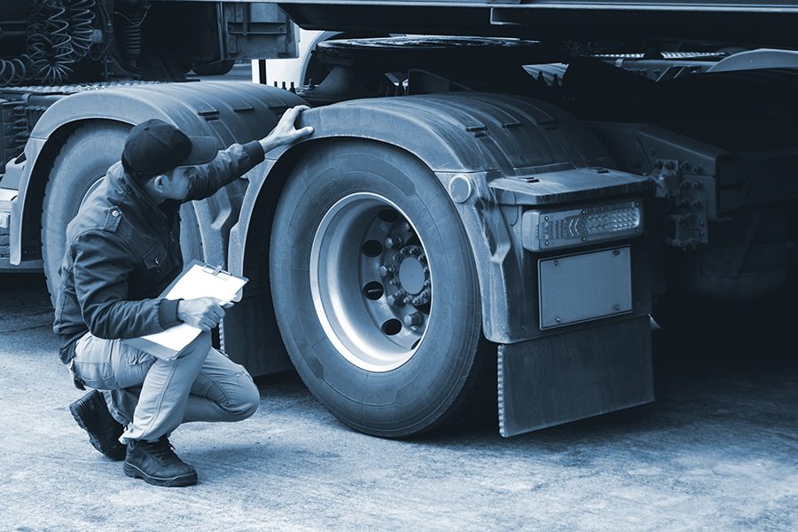Truck driver inspects tires for saftey