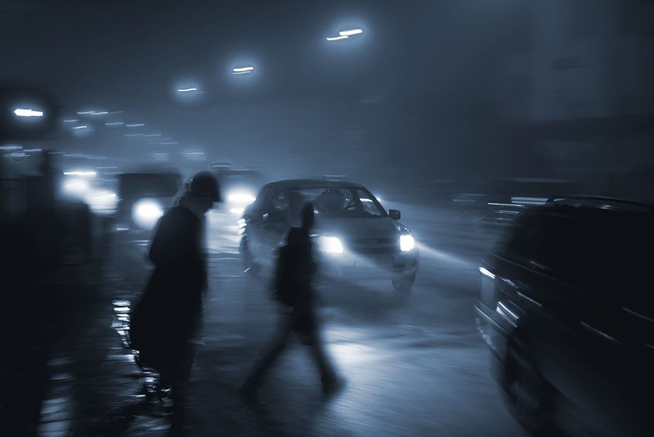 Blurring night shot of pedestrians walking across a busy street
