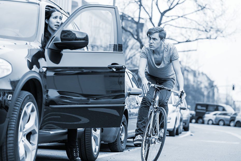 bicyclist swerves to avoid hitting an open car door. 