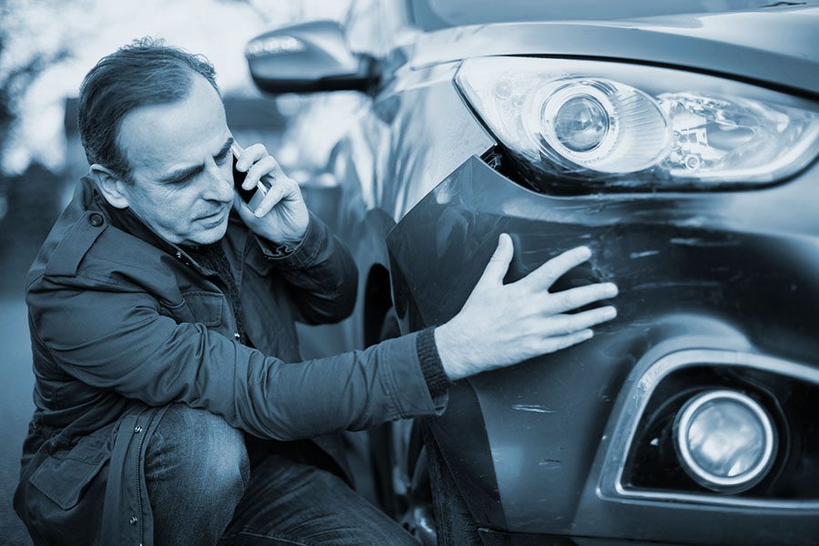 Mature man addresses car damage while on the phone