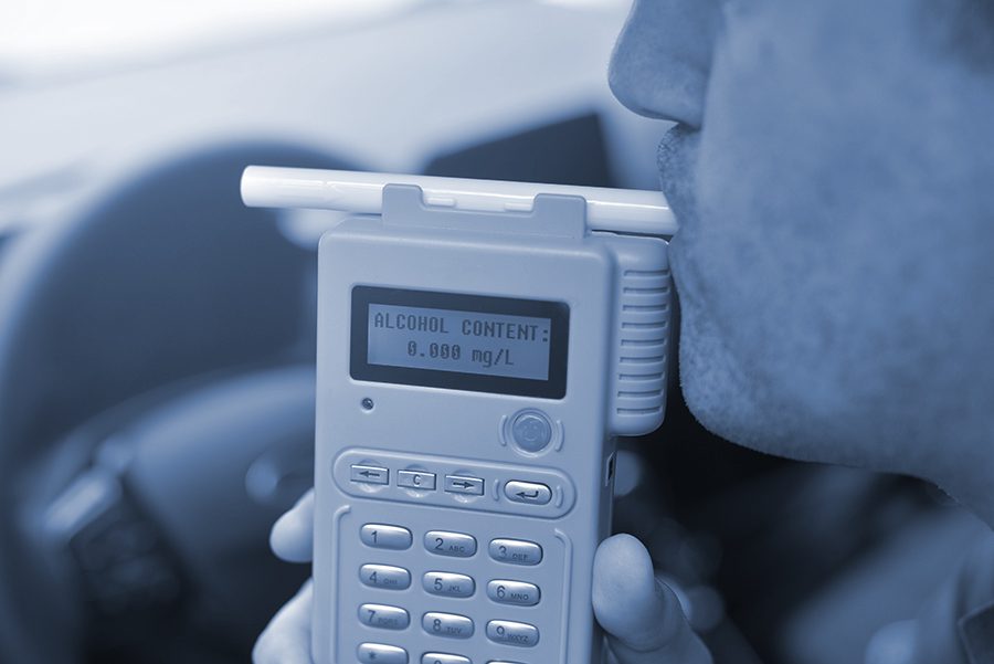Man blows into a breathalyzer to check for blood alcohol content