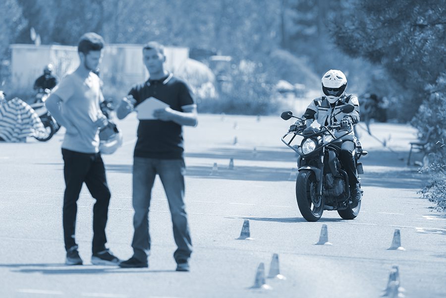 Motorcyclist rides the motorcycle safety course while instructor works with another student