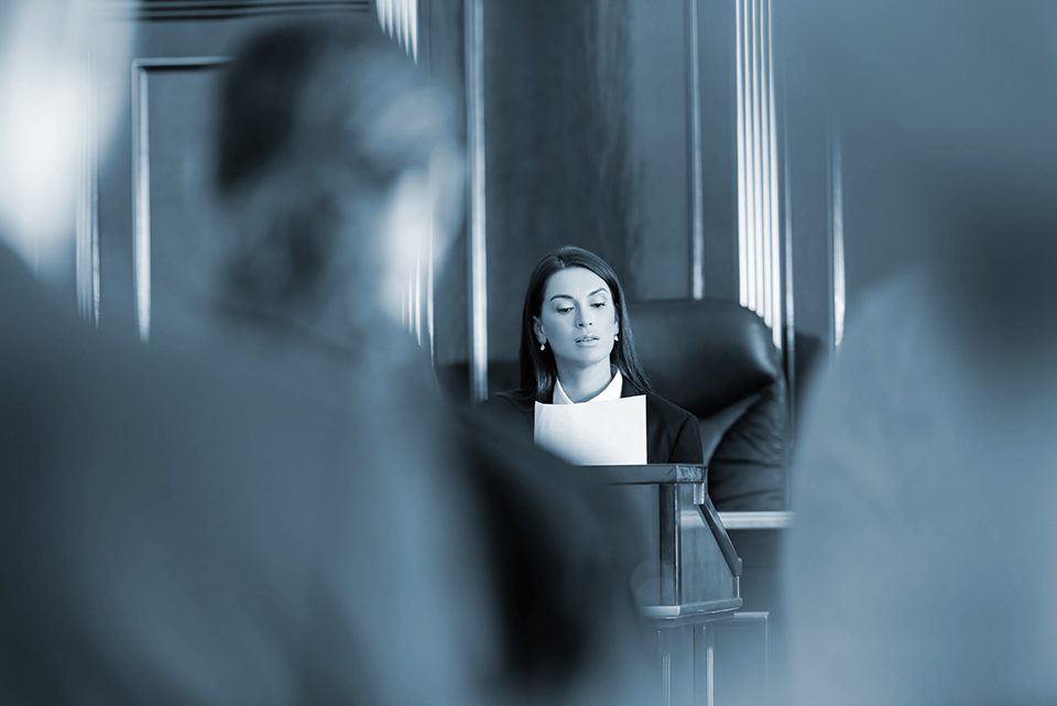 Judge reading lawsuit in court framed by blurred foreground