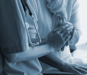 Doctor comforting patient by holding their hand