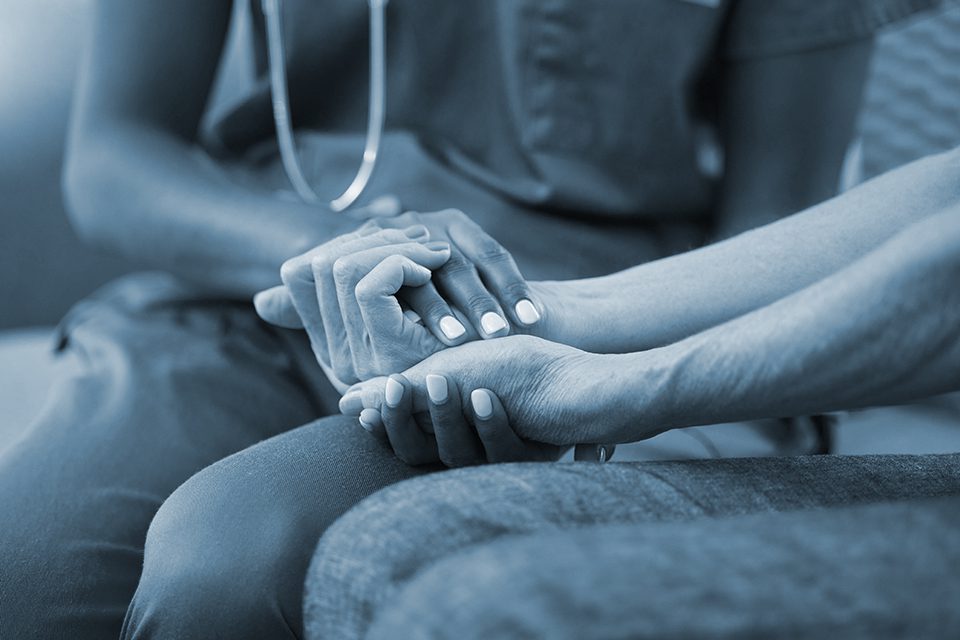 Doctor holds patient's hand during at home consultation