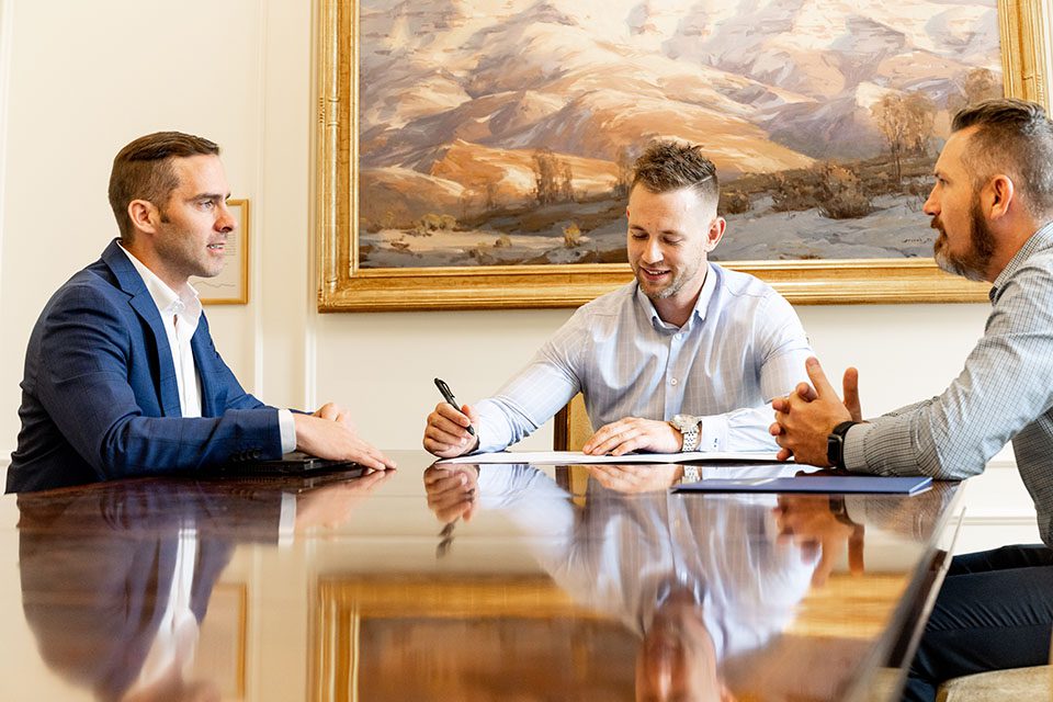 Lawyer writes down notes at the head of a long table