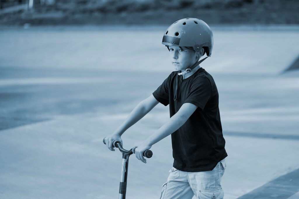 child rides a scooter while wearing a helmet