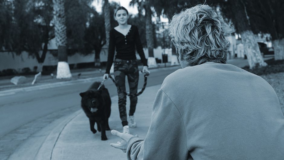 Women welcomes a leased black dog on the sidewalk