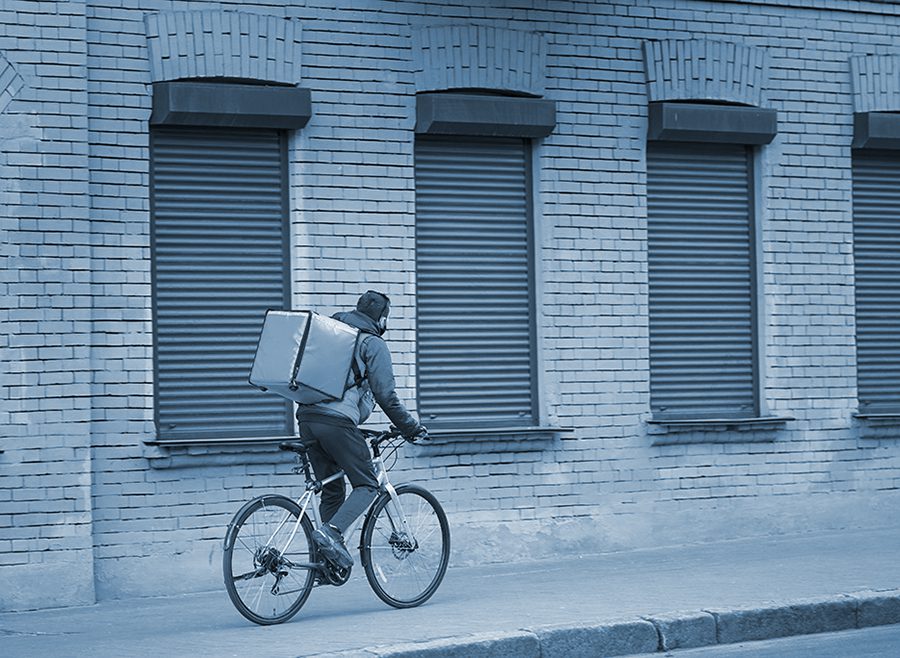 Delivery bicyclist rides on the sidewalk in a city