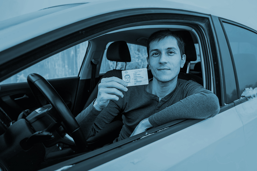 Caucasian man shows his driver's license in the car window immediately after passing the exam or at the request of the traffic police
