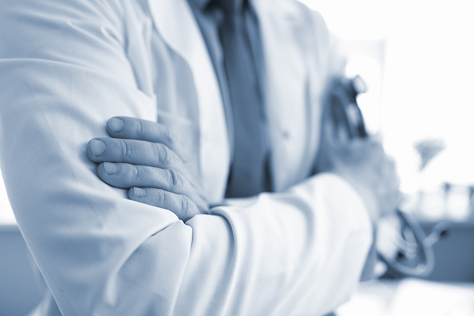 Hands of doctor in white coat holding stethoscope