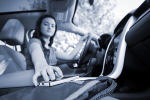 A distracted driver reaches for her cell phone
