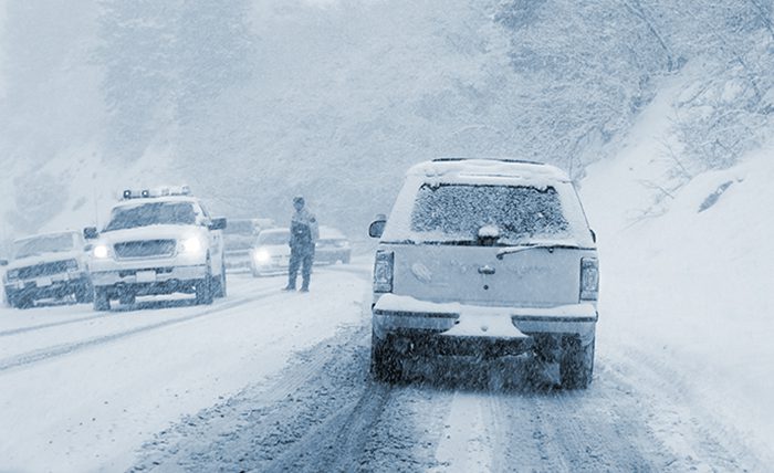 A car drives in dangerous winter road conditions during a snowstorm