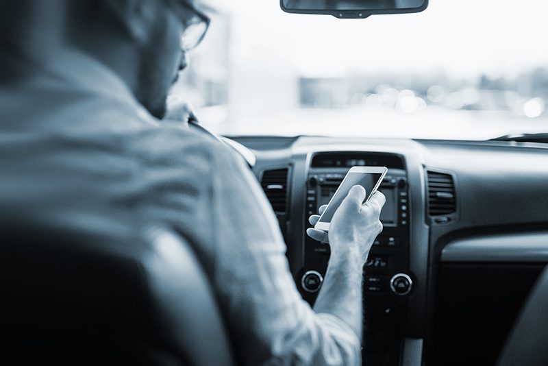 man using phone while driving the car