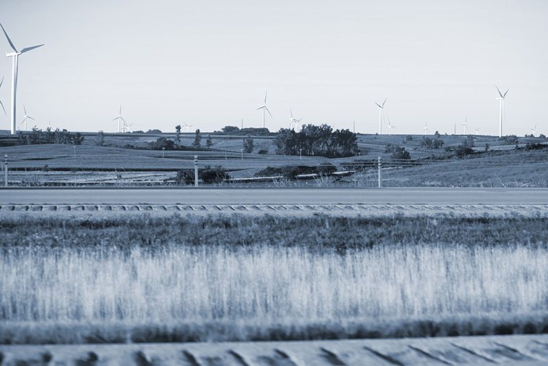 Scenic country road with wind turbines.