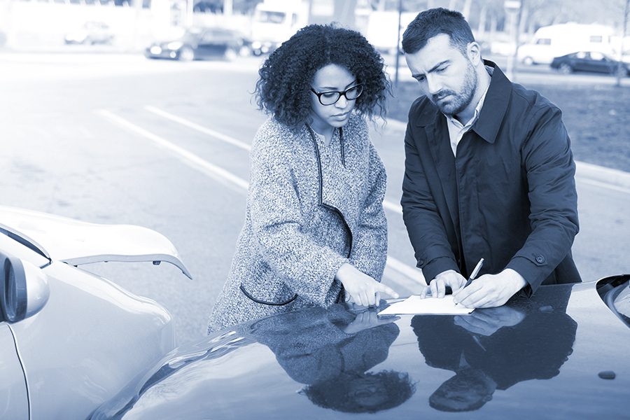 Man and woman filling an insurance car form after bad car crash