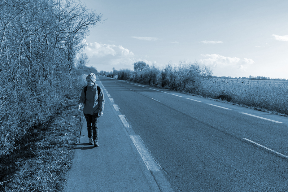Girl walking on the shoulder of a lonely abandoned road